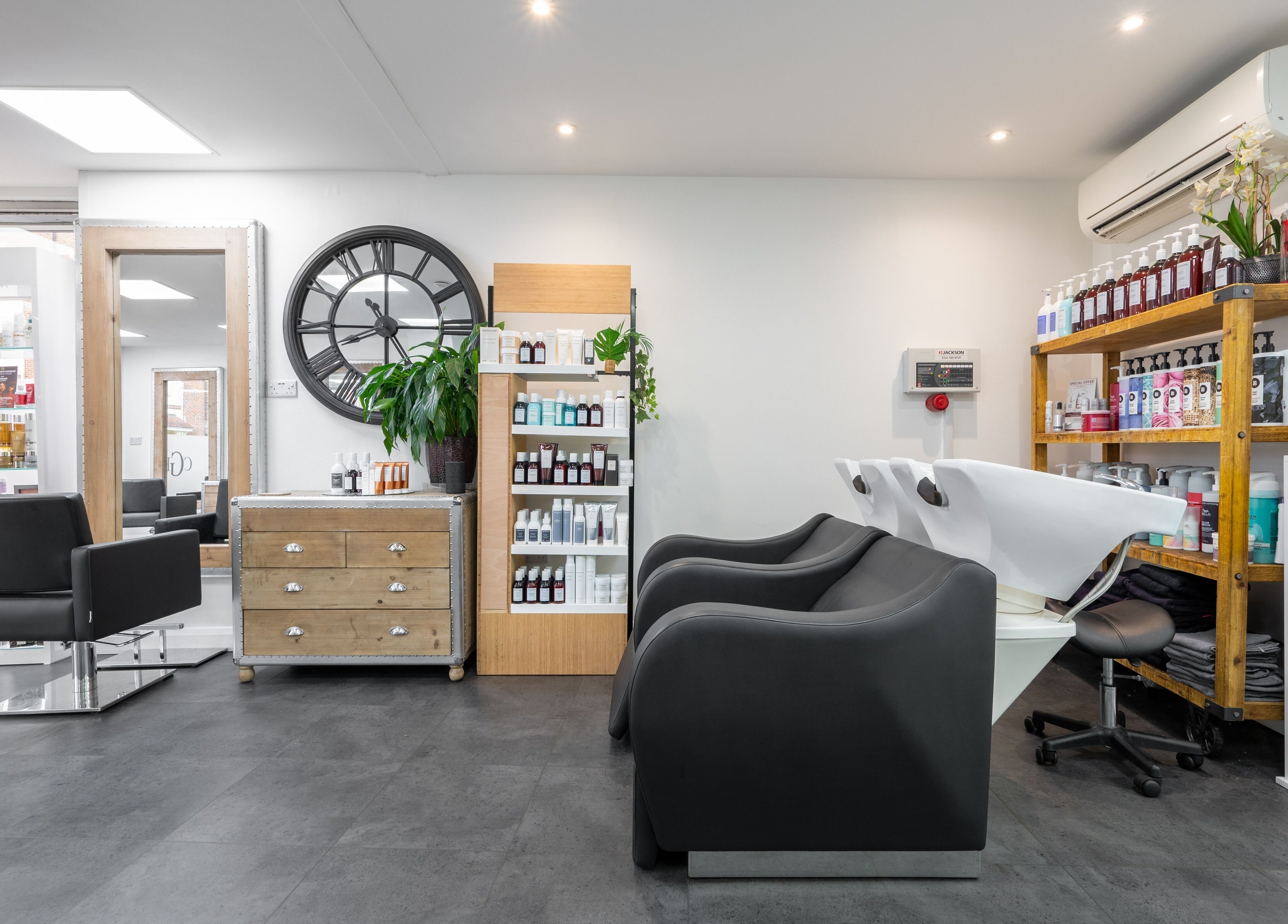 Chic and modern interior of Cara Gibbs Hairdressing in Sale, England, GB featuring stylish salon chairs and products.