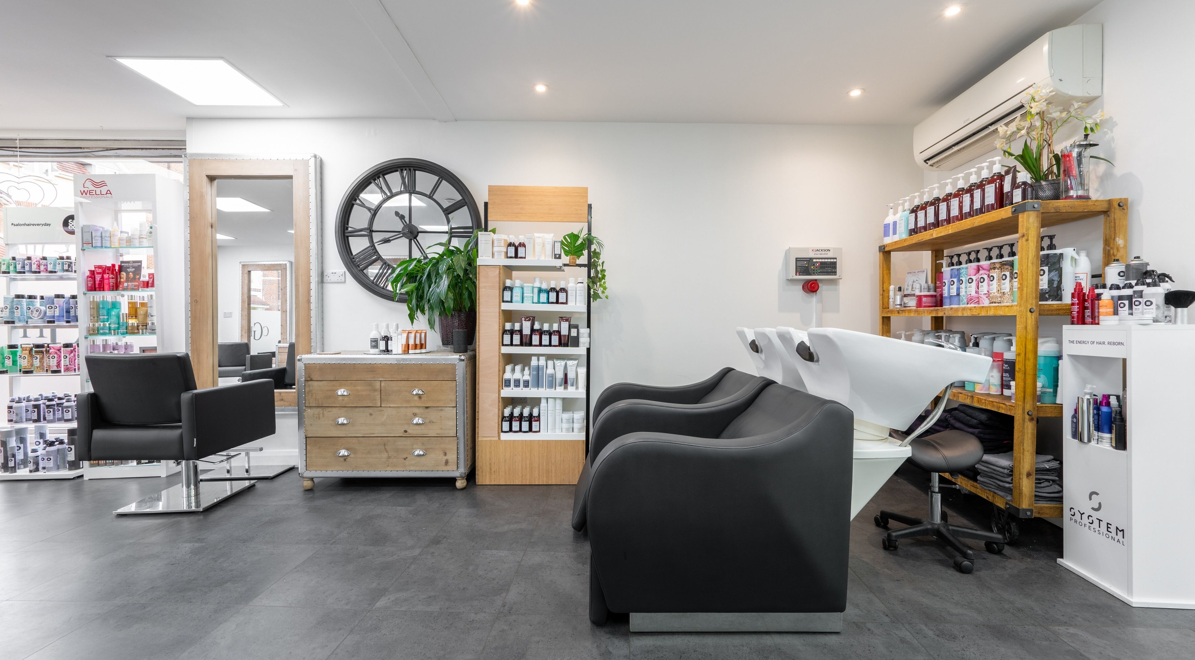 Chic and modern interior of Cara Gibbs Hairdressing in Sale, England, GB featuring stylish salon chairs and products.