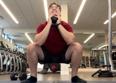 Man performing a squat with a kettlebell at MarkSpeakForm gym in Howell, Michigan, US.