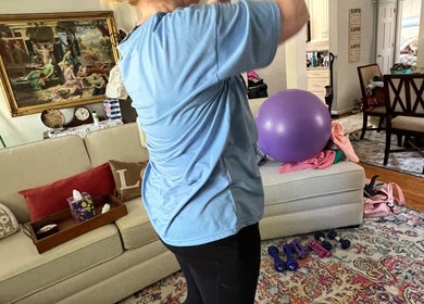 A woman exercising in a cozy living room at MarkSpeakForm in Howell, Michigan, US with a yoga ball and weights.