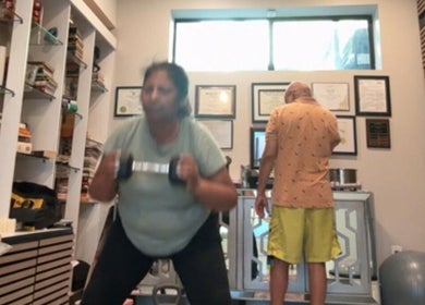 Workout session at Marks Peak Form gym in Howell, Michigan, US. Woman using dumbbells with certificates in view.