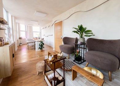 Cozy seating area at Lani Nails London, GB with plush chairs, indoor plants, and wooden decor.
