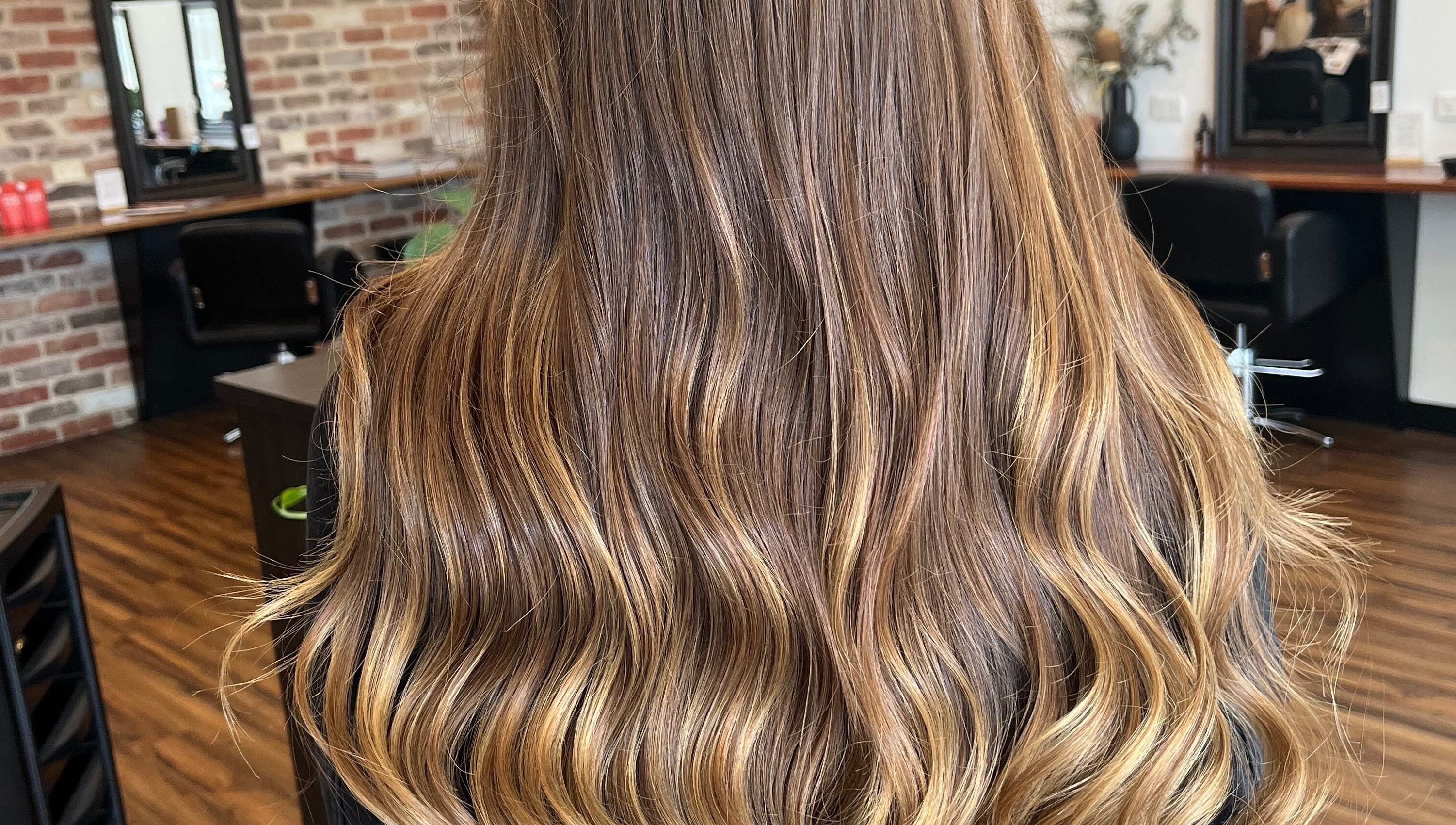 Glossy, wavy hair with caramel highlights at BROW’D beauty & co, Redbank Plains, Queensland, AU.