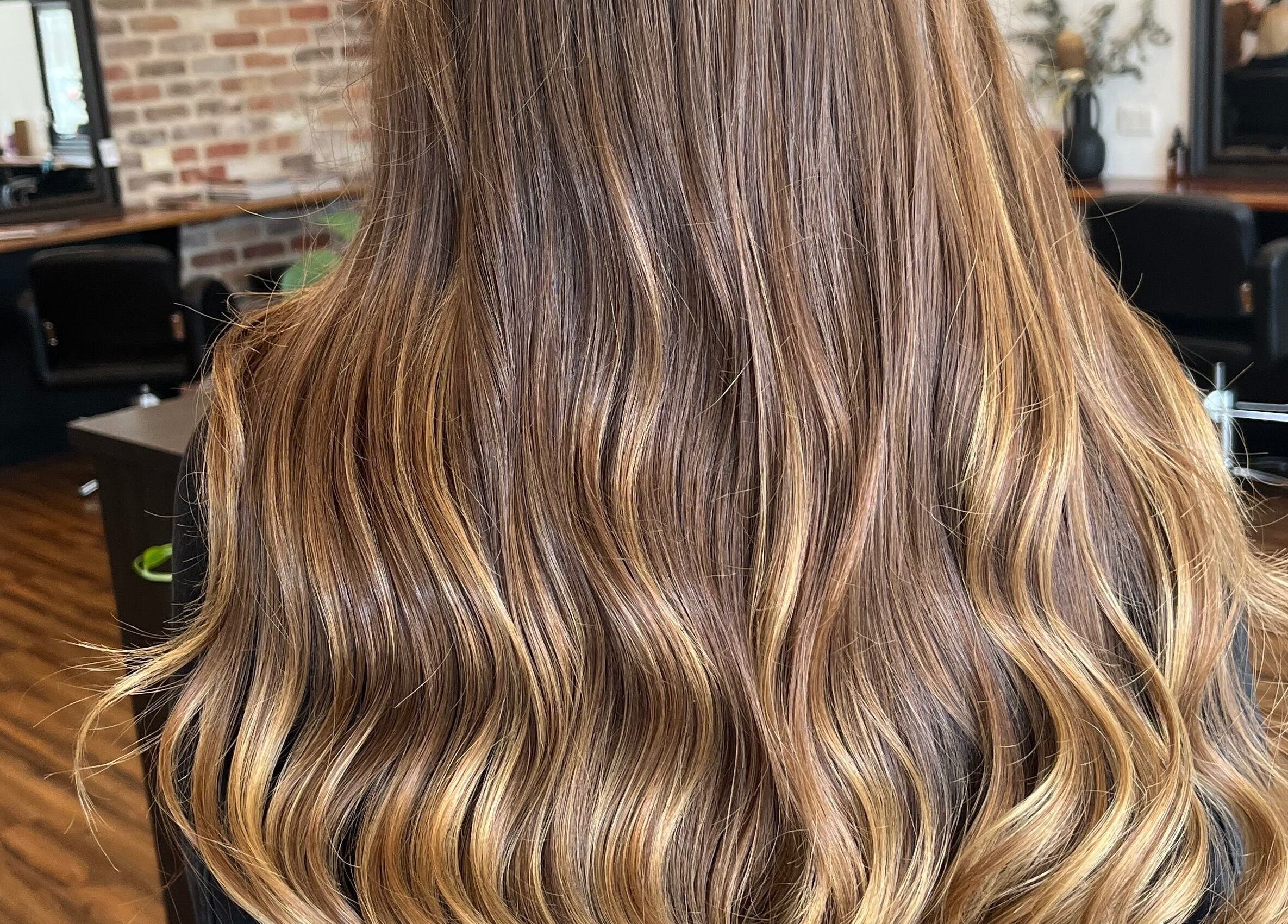 Glossy, wavy hair with caramel highlights at BROW’D beauty & co, Redbank Plains, Queensland, AU.