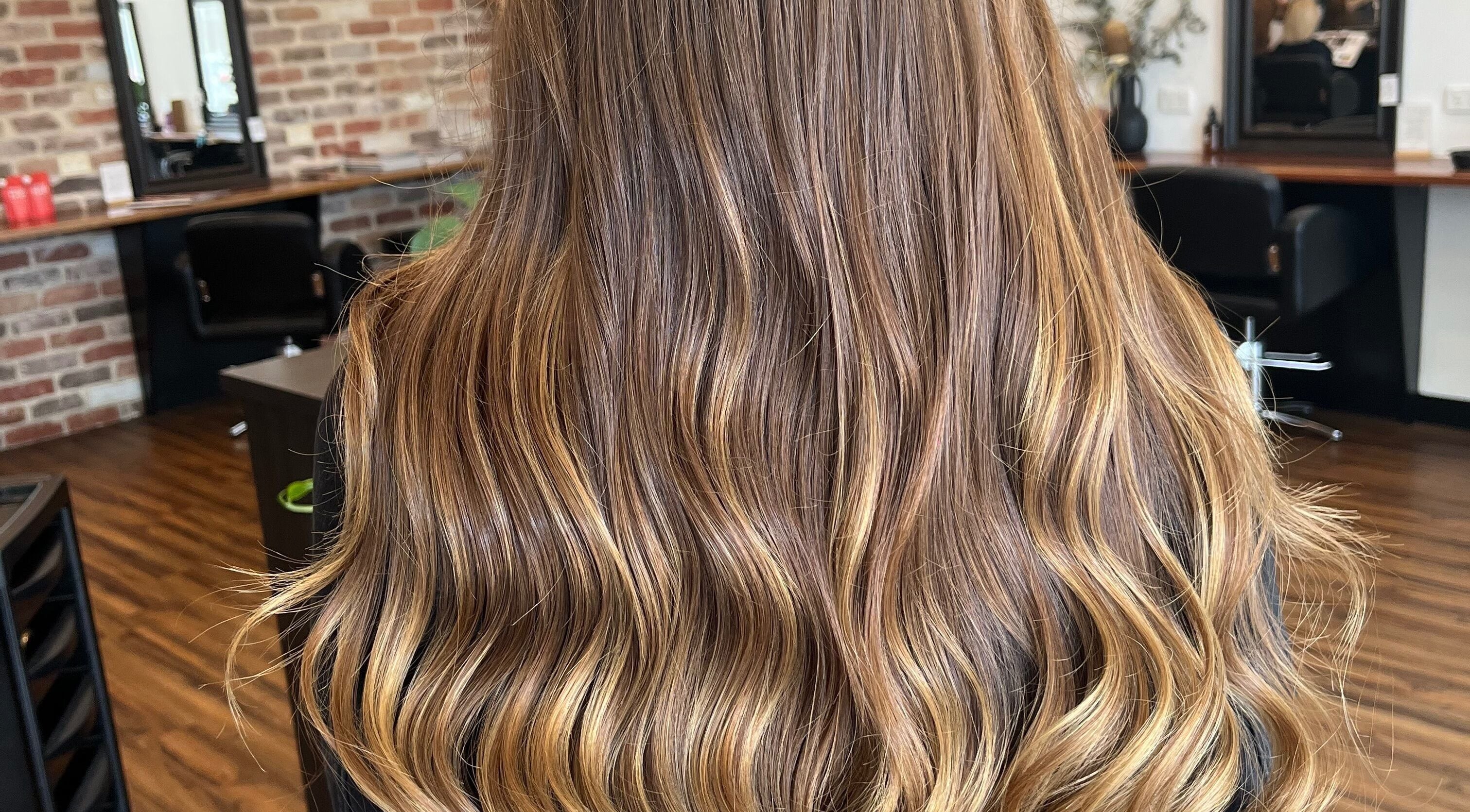 Glossy, wavy hair with caramel highlights at BROW’D beauty & co, Redbank Plains, Queensland, AU.