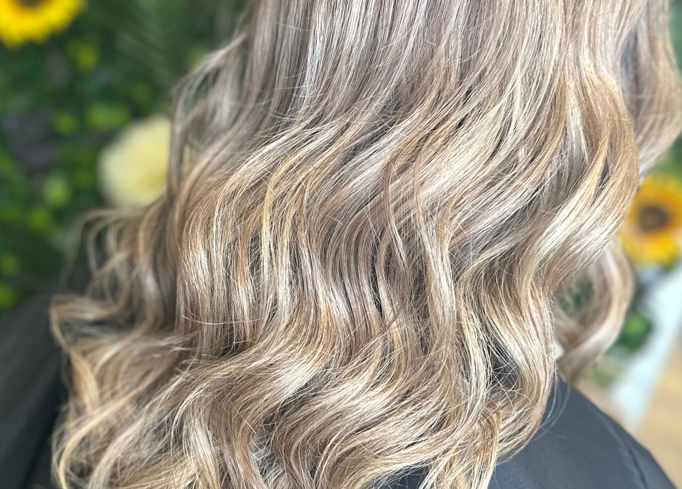 Blonde waves styled at Thistles by Bethany Danielle Hair in Carlisle, England, GB with a floral backdrop.