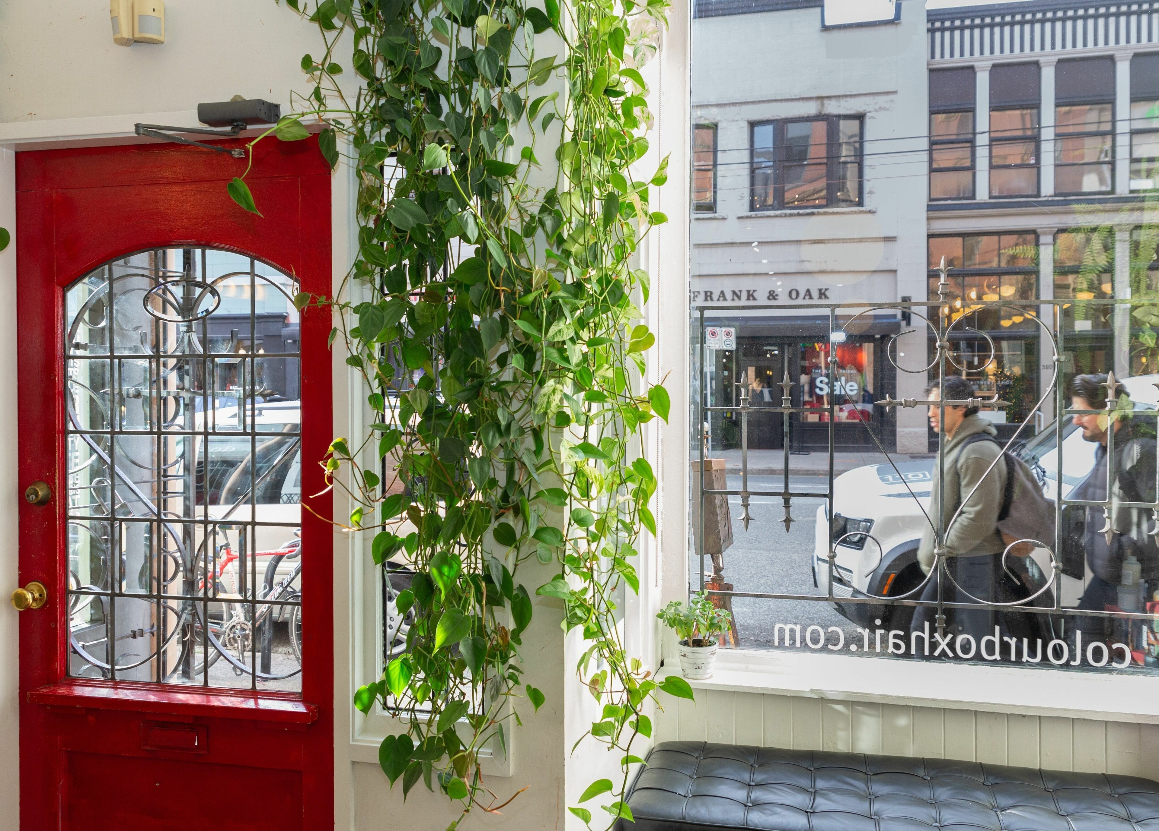 Inviting red door with lush greenery at Colourbox, Vancouver, British Columbia, CA.
