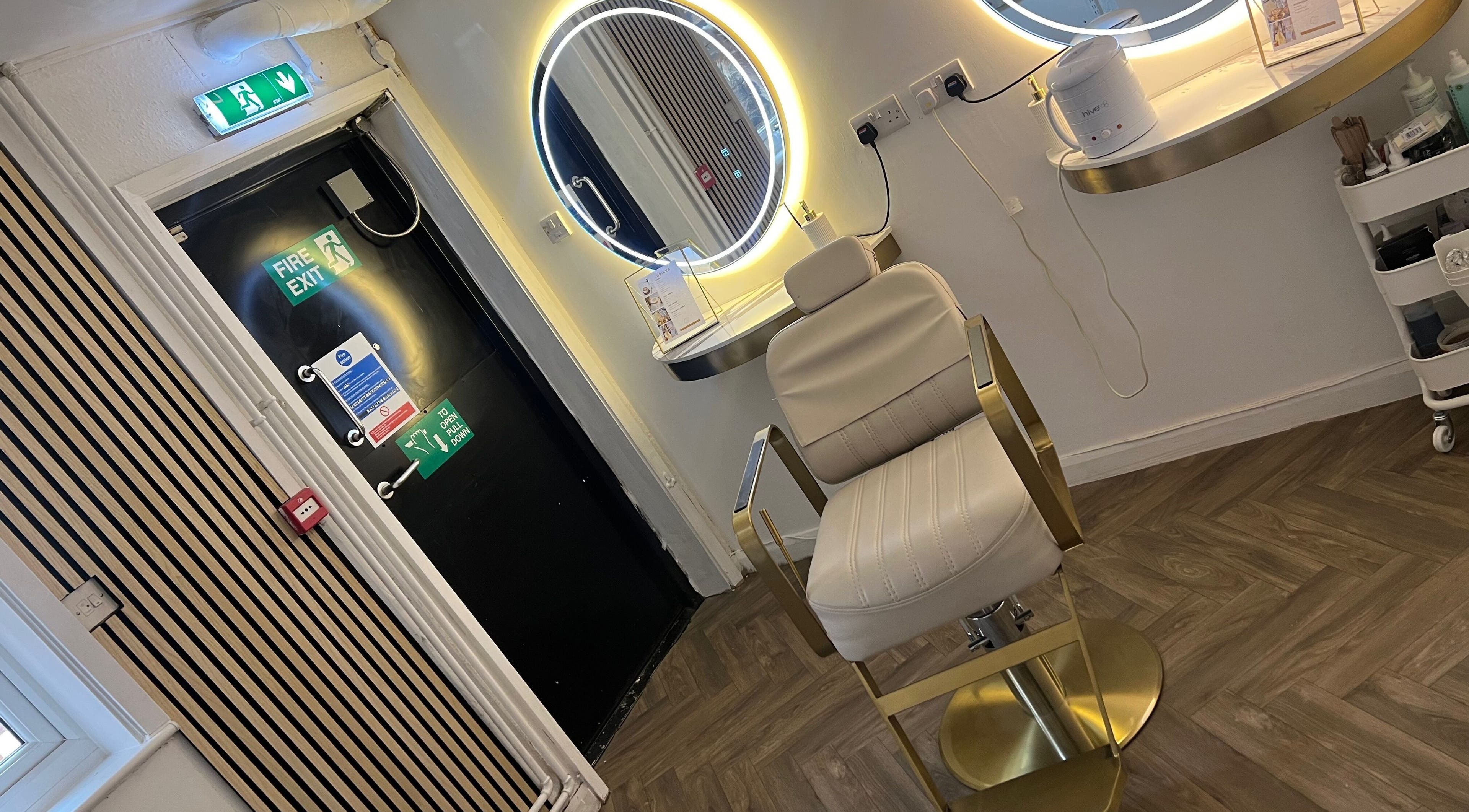 Chic interior of GLO by Holly-mae in Syston, England with luxurious treatment chair and illuminated mirrors.