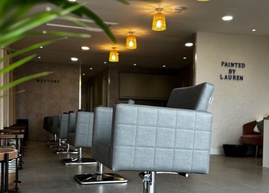 Modern salon interior at Neptune in Livingston, Scotland. Elegant seating and warm lighting create inviting atmosphere.