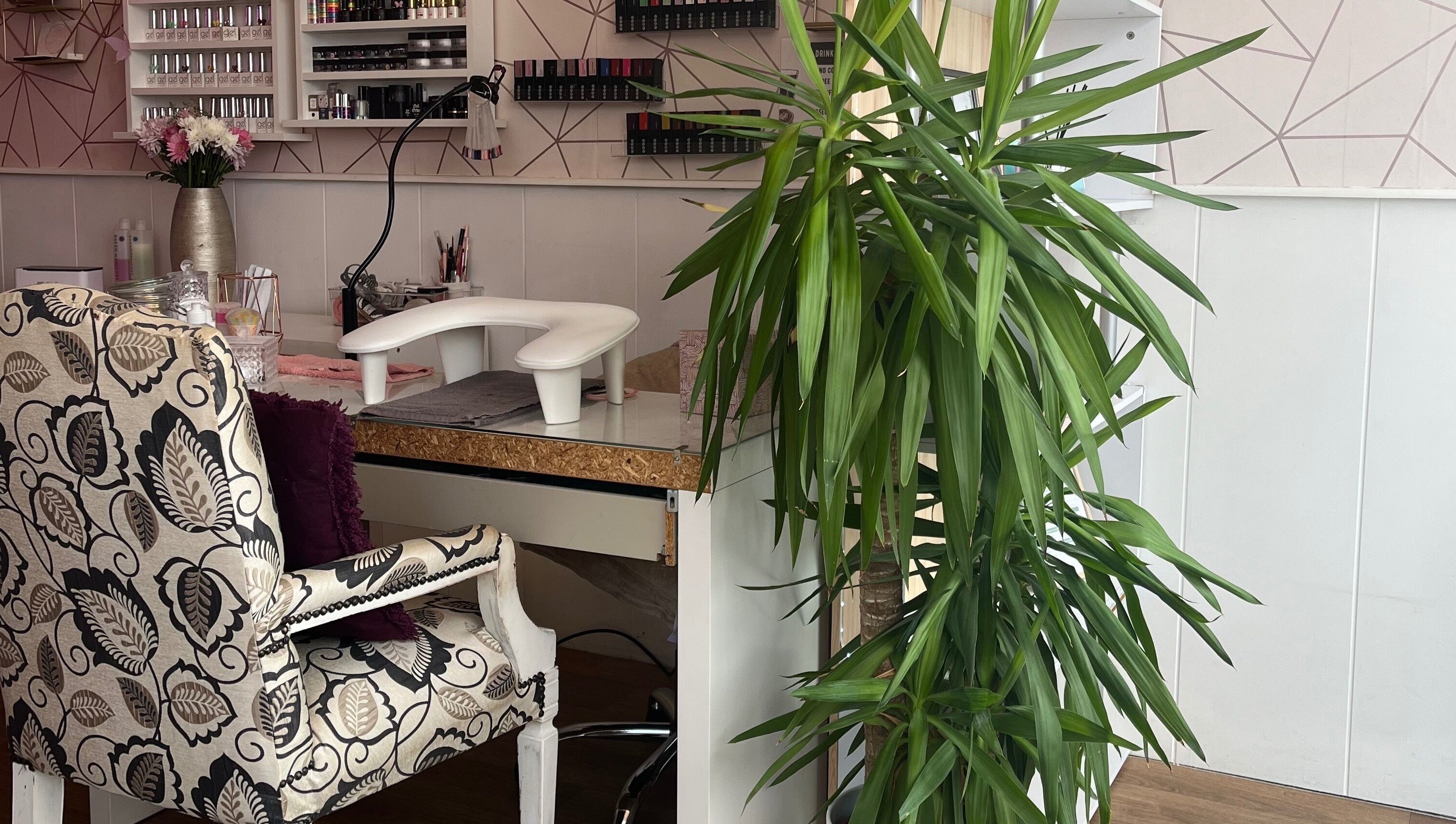 Elegant beauty salon corner at All About You, St Austell, England, GB with patterned chair and lush plant.