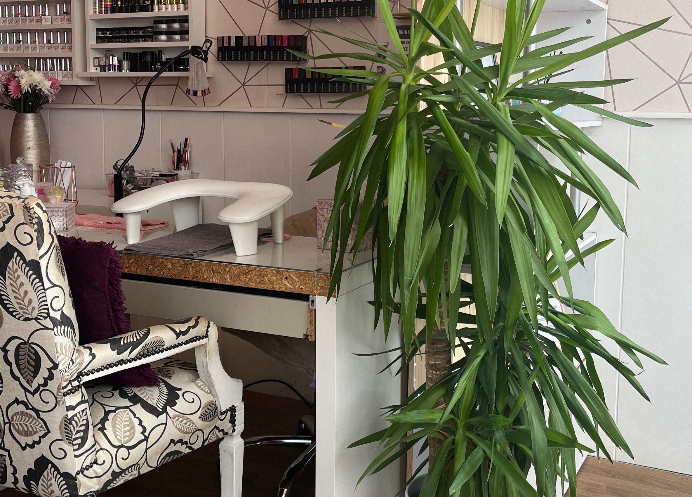 Elegant beauty salon corner at All About You, St Austell, England, GB with patterned chair and lush plant.