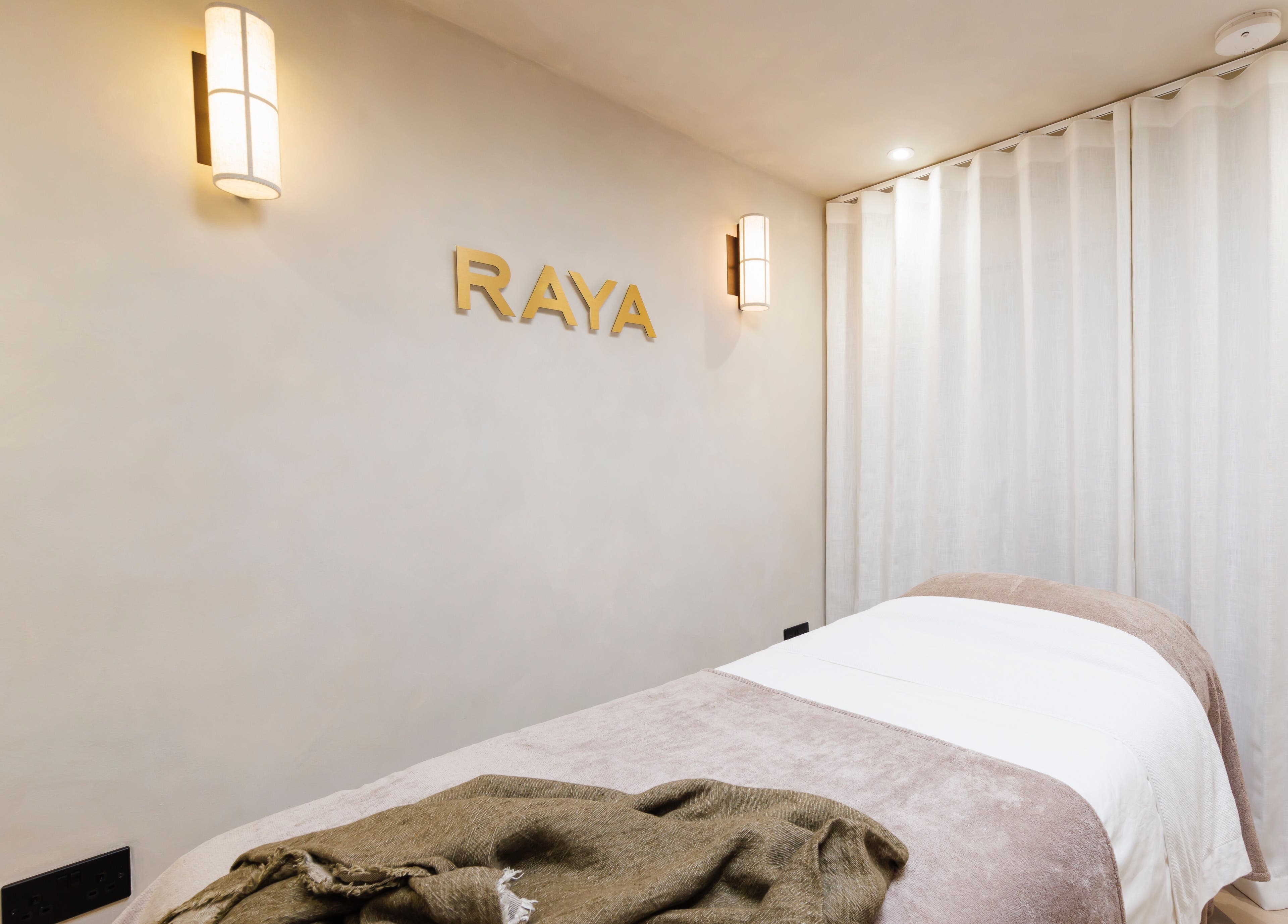 Relaxing treatment room at Raya Clinic - Skin, PMU & Aesthetics, Havant, England, GB, with a cozy bed and soft lighting.