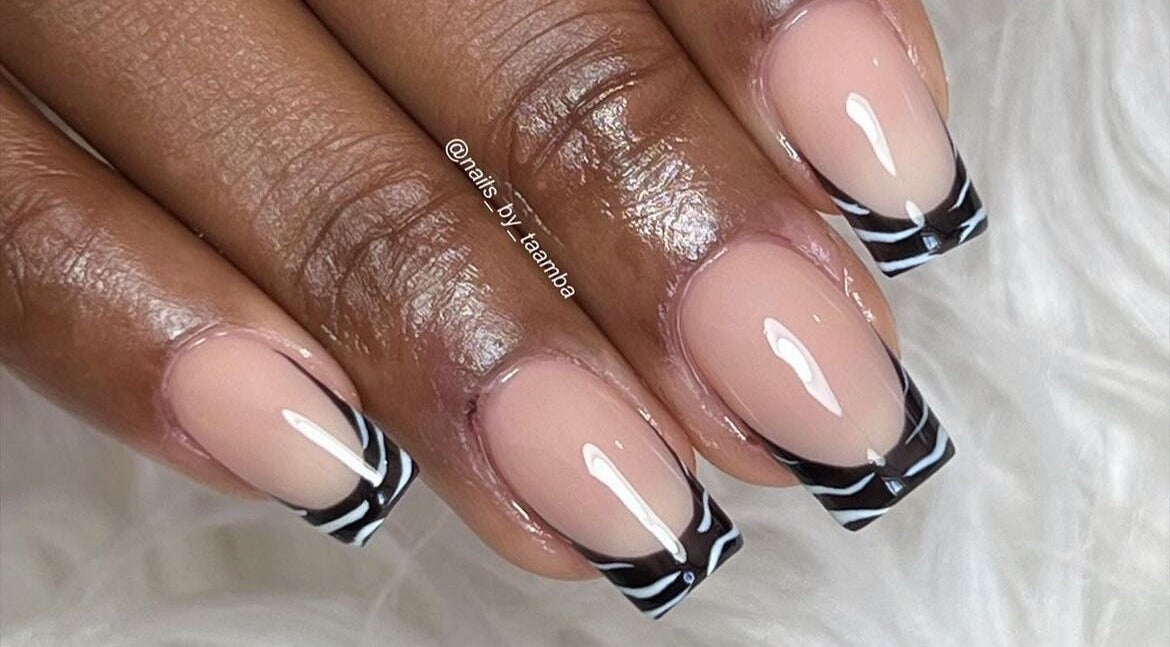Stylish zebra French tip nails by Nails by Taamba in Windhoek, Khomas Region, NA on a fluffy white background.