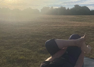 Outdoor yoga at sunset on a field at The Retreat New Forest, Christchurch, Dorset, GB.