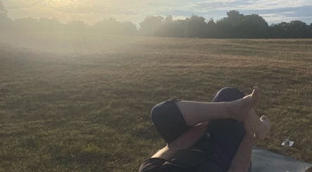 Outdoor yoga at sunset on a field at The Retreat New Forest, Christchurch, Dorset, GB.