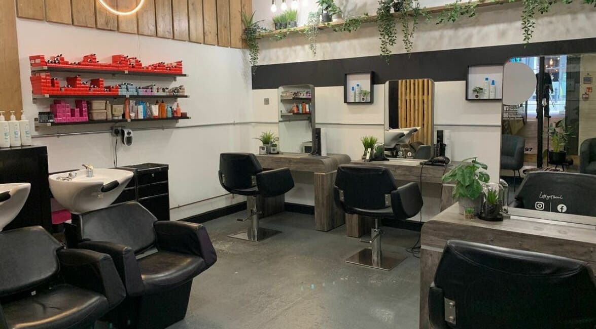 Modern salon interior at Eden, Sheffield, England, GB, featuring sleek styling stations and lush greenery.