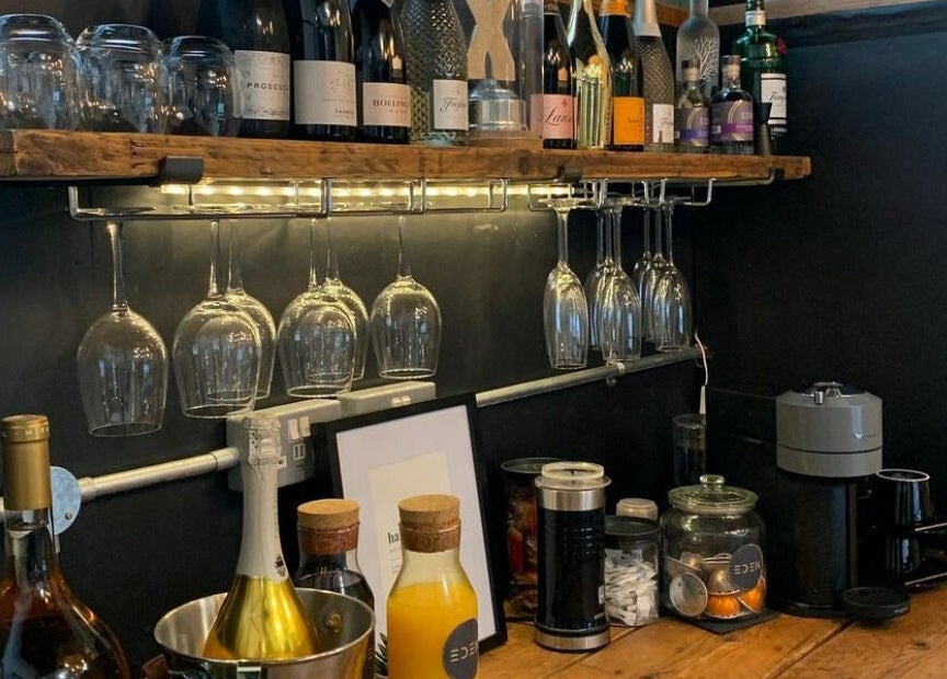 Chic wine display at Eden, Sheffield, England, GB featuring bottles and glasses on rustic shelves.