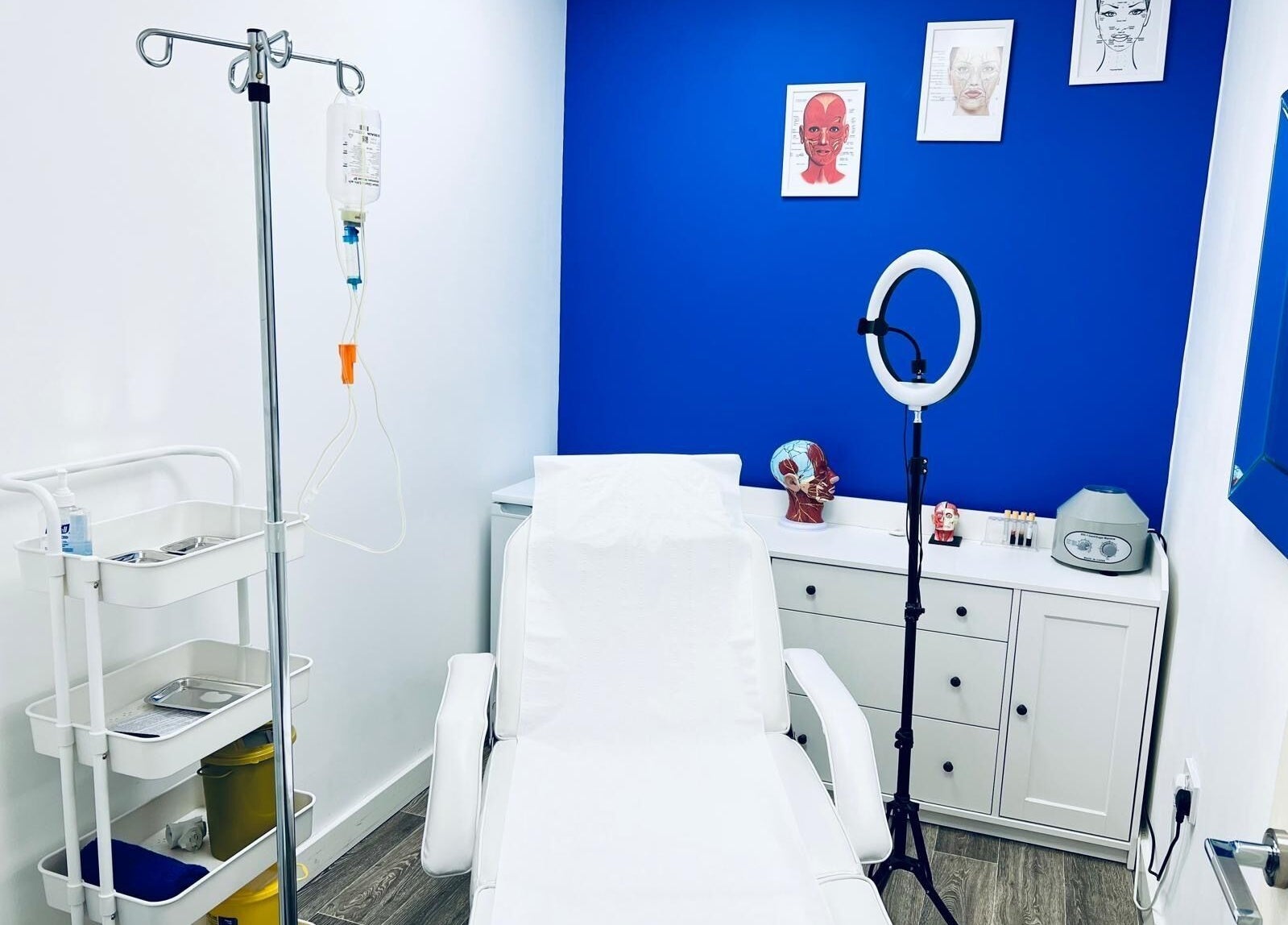 Modern treatment room at Beautifly Romford, England with white chair and vibrant blue wall.