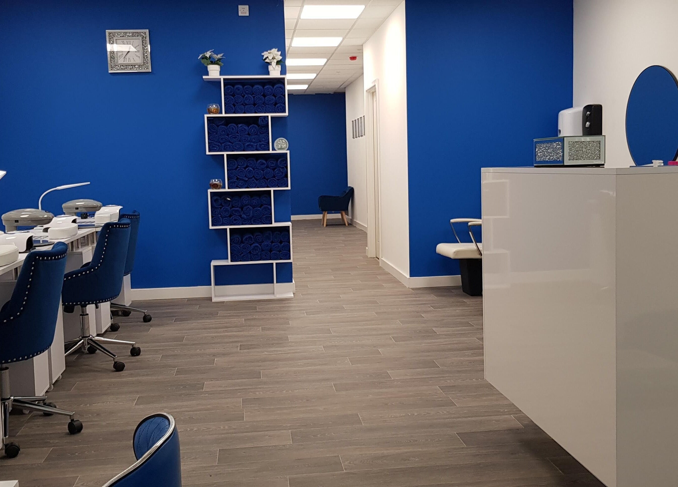 Modern nail salon interior at Beautifly, Romford, England, GB featuring elegant blue decor and neat workstations.