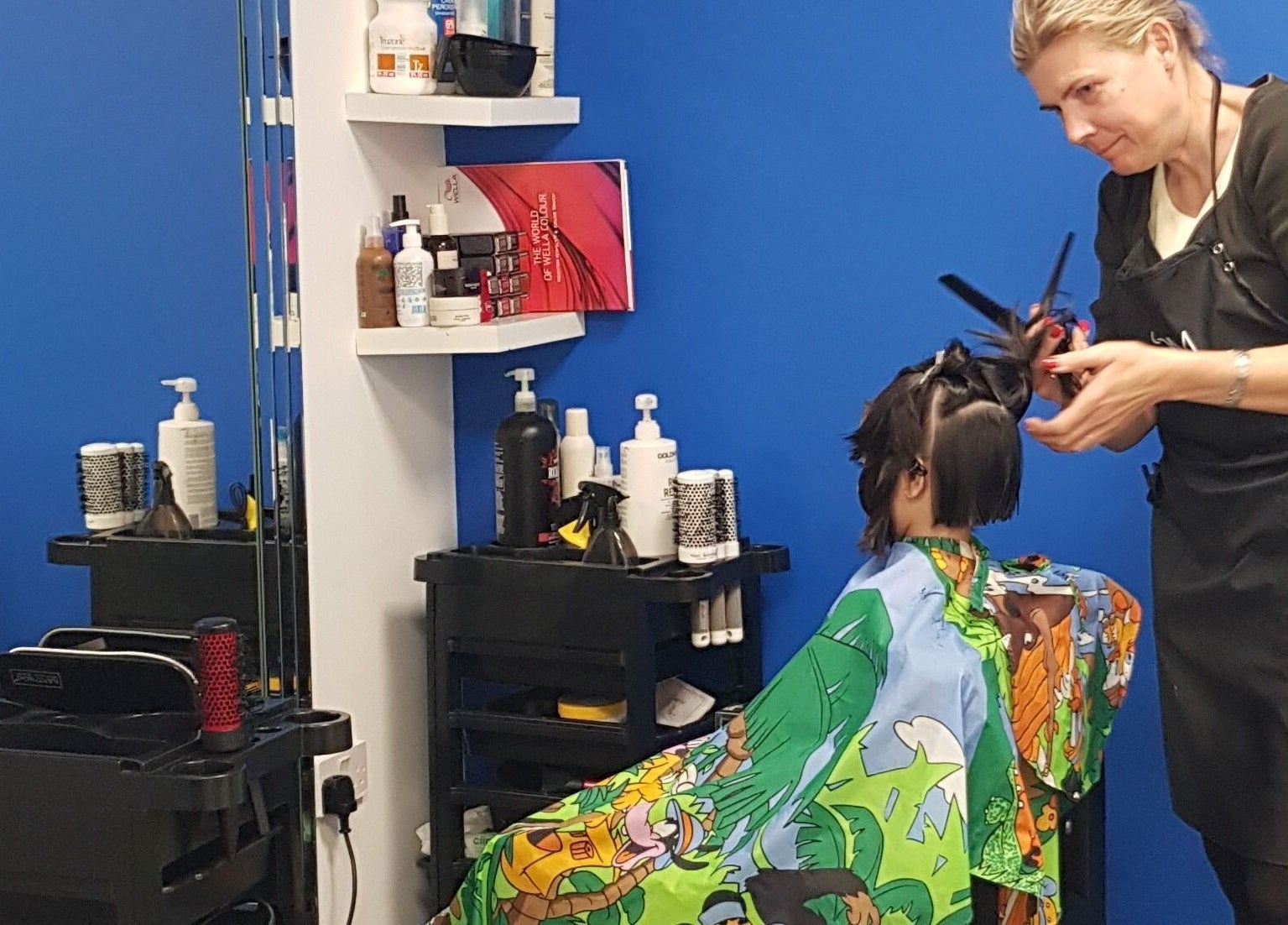 Hairdresser styling a child's hair at Beautifly in Romford, England, GB. Professional salon service.