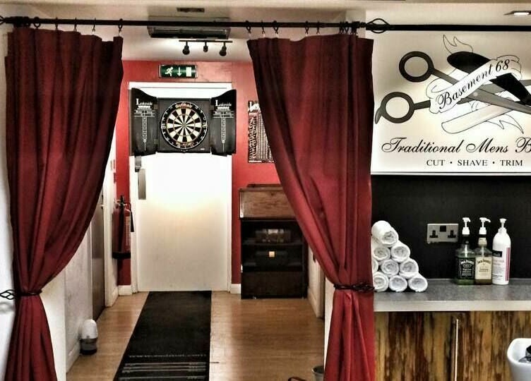 Cozy interior of Basement 68 Barbers in Leeds, England, GB with rich curtains and classic decor.