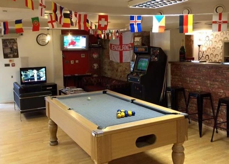 Pool table and lounge area at Basement 68 Barbers, Leeds, England, GB with flags and entertainment setup.