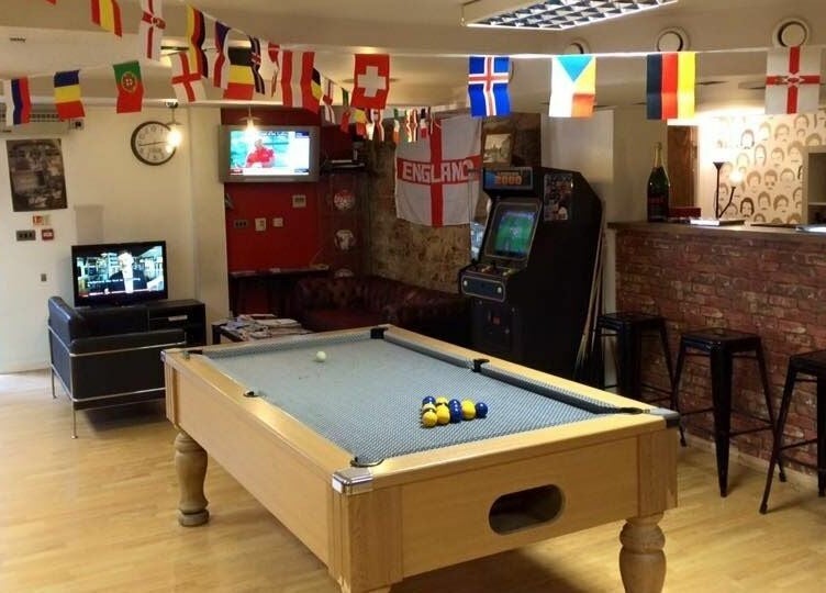 Pool table and lounge area at Basement 68 Barbers, Leeds, England, GB with flags and entertainment setup.