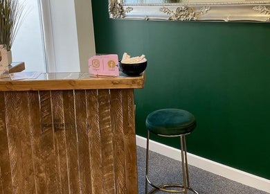 The Beauty Hut Pontyclun reception with a wooden desk and green stool, Pontyclun, Wales, GB.