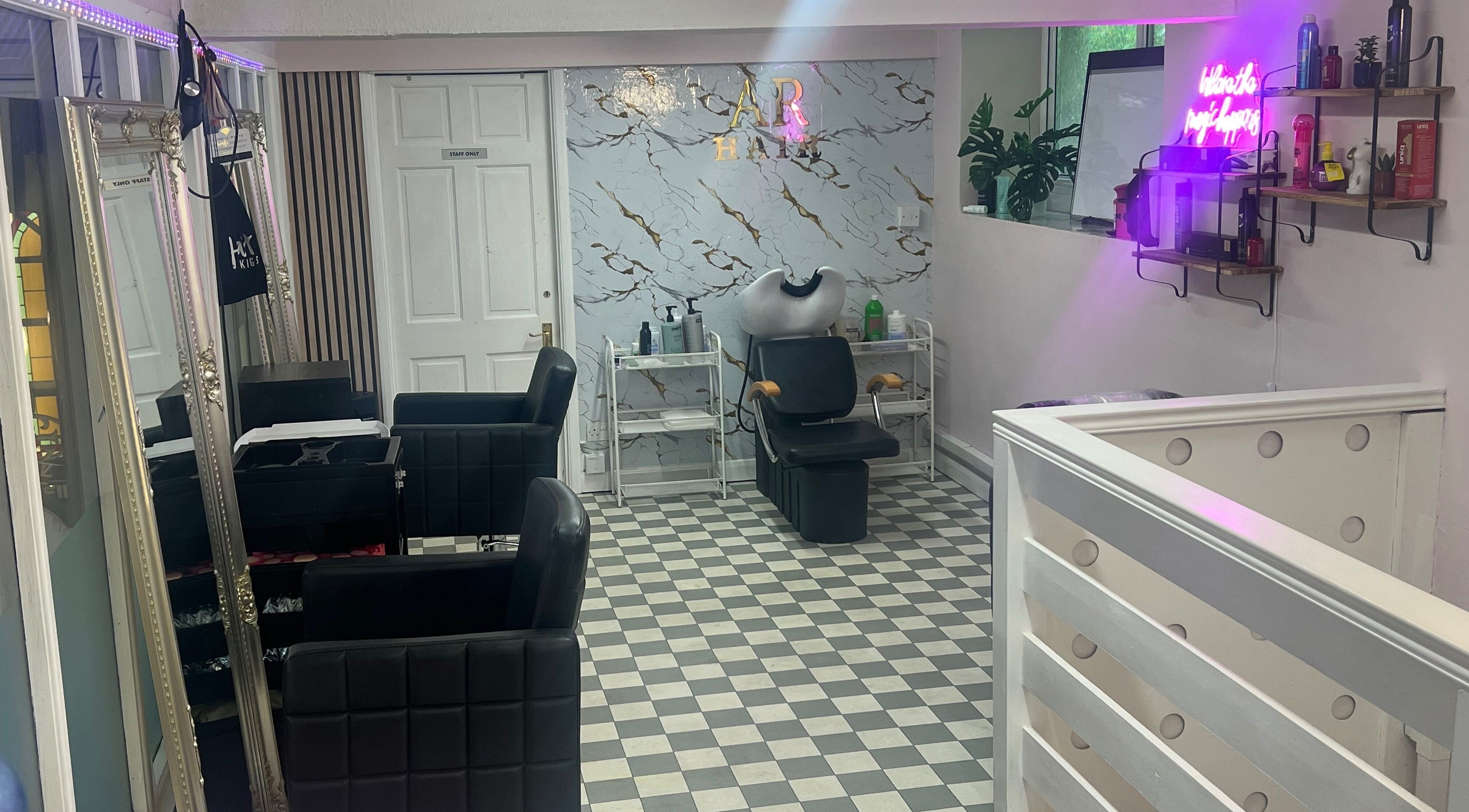 Chic interior of AR Hair & Beauty Lounge in Arundel, England, GB with stylish black chairs and marble wall.