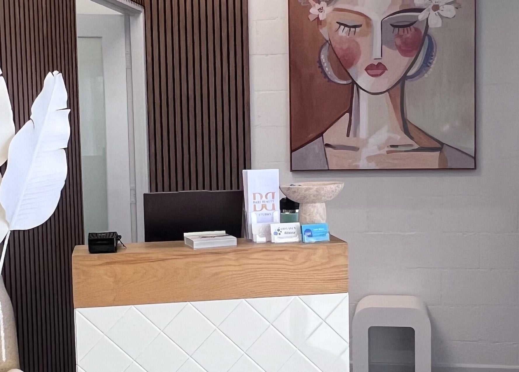 Modern reception desk at Bare Beauté, Mareeba, Queensland, AU, with artistic wall décor and elegant furnishings.