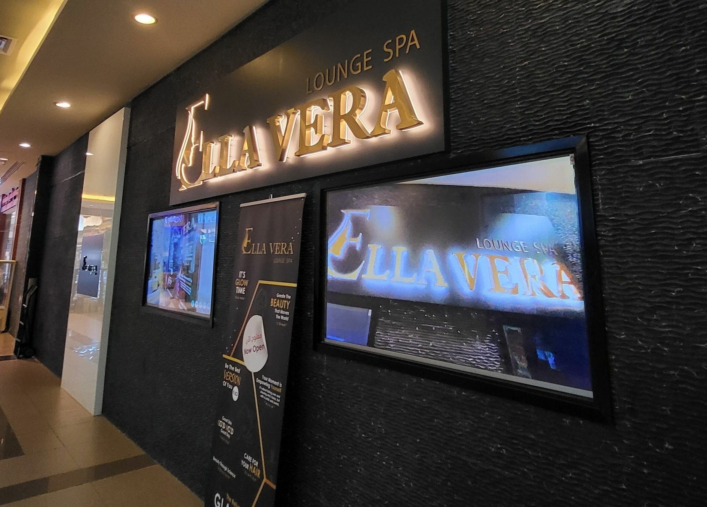 Entrance of Ella Vera Lounge Spa in Al Ain, AE, featuring illuminated signage and stylish interior design.