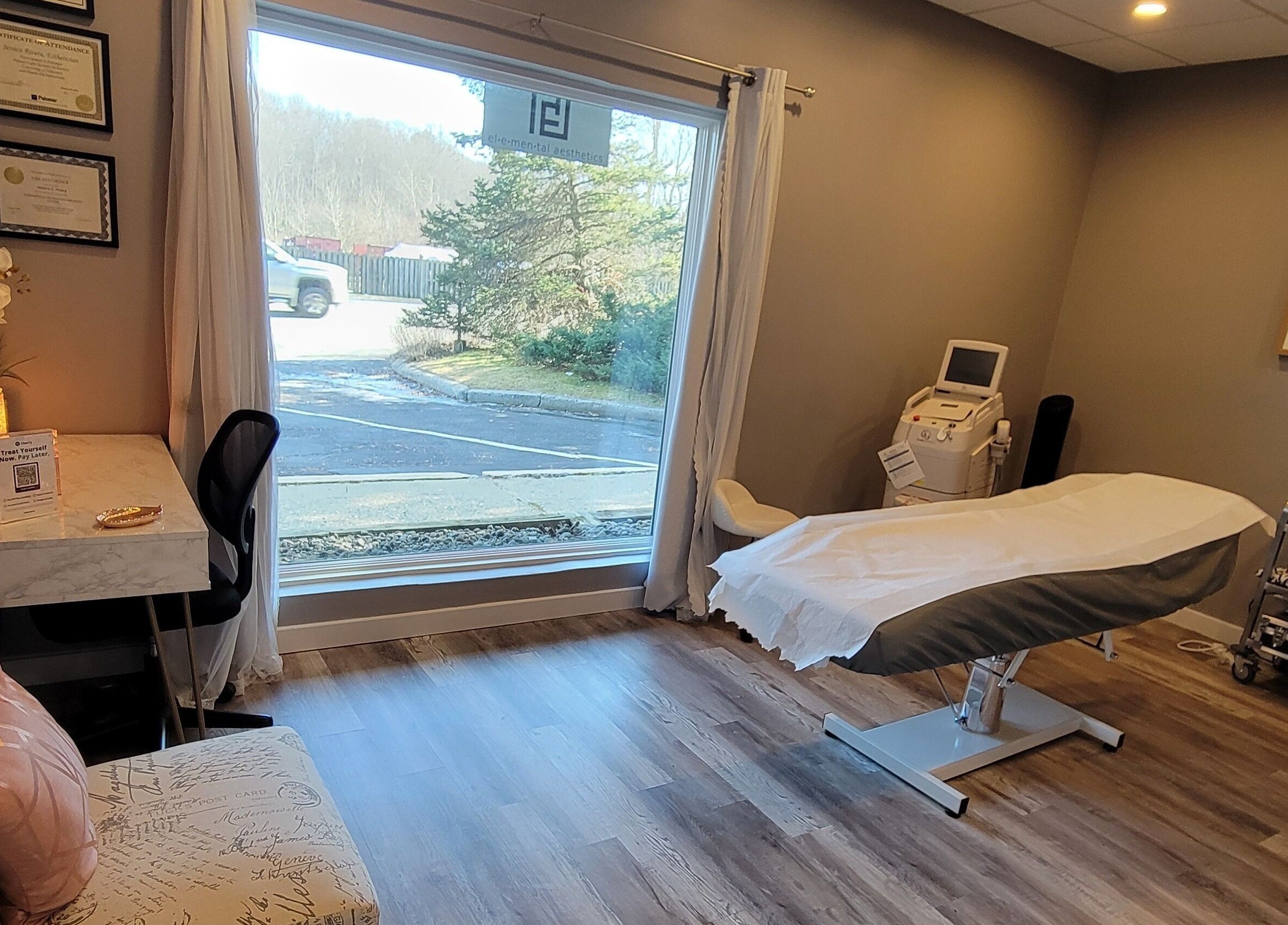 Cozy treatment room at Elemental Aesthetics, Mahopac, New York, US with a bed and large window view.