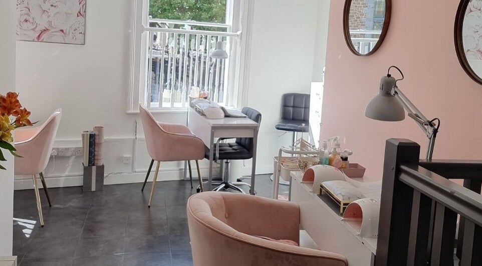 Bright, elegant nail tables at Rita&Phil’s Salon in Guernsey, Saint Peter Port, GG, with soft pink chairs.