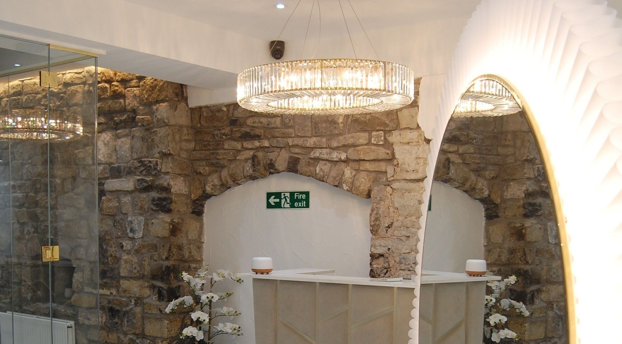 Elegant stone and glass interior at Skinfix Clinic, Penarth, GB featuring chic lighting and decorative plants.
