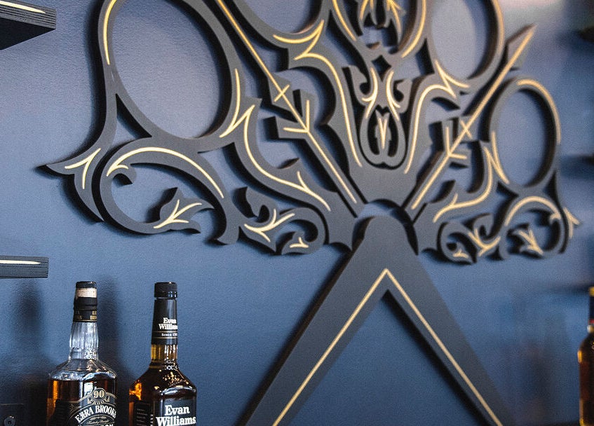 Intricate wall art at Throne Traditional Barbershop on Williams, Portland, Oregon, US, with spirits displayed on shelves.