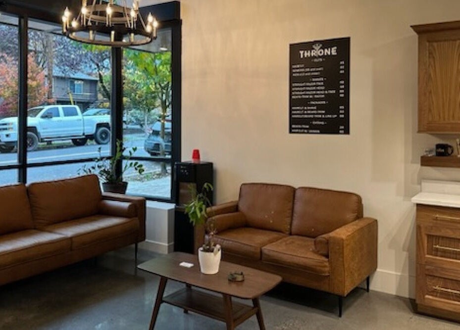 Cozy lounge area at Throne Traditional Barbershop on Division, Portland, Oregon, US, featuring brown leather sofas.