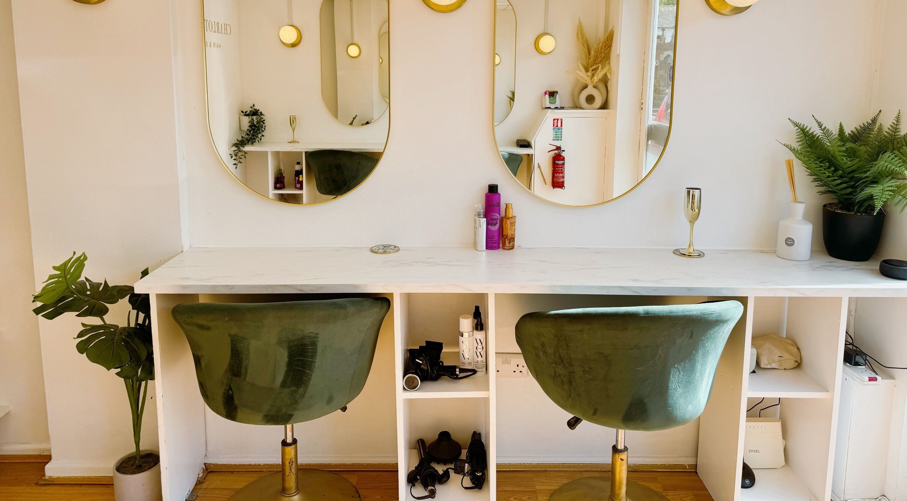 Modern beauty station at Charlotte Liberty Hair & Beauty, Shoreham-by-Sea, England, GB with green chairs and mirrors.