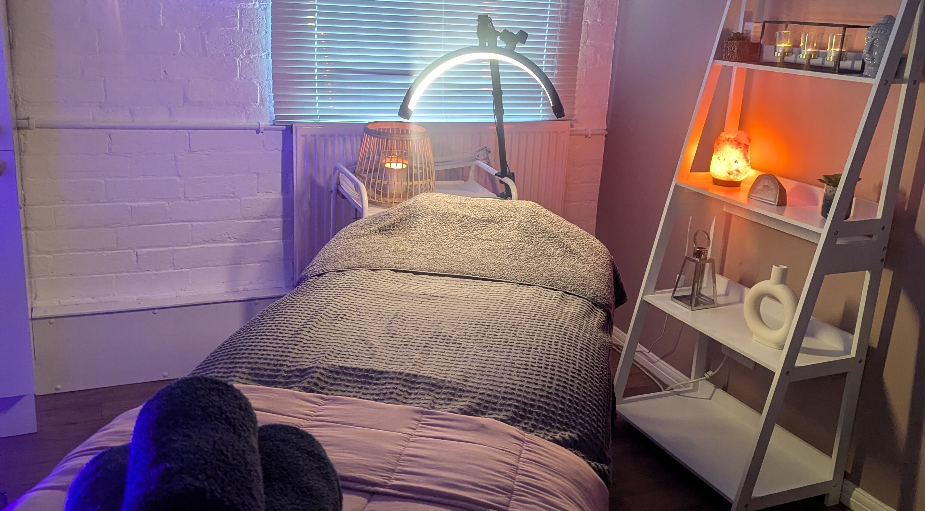 Cozy treatment room at Eloquin in Basingstoke, England, GB, featuring ambient lighting and a relaxing bed.