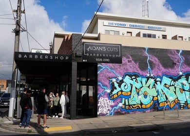Aidans Cuts Barbershop facade with colorful graffiti in Melbourne, Victoria, AU.
