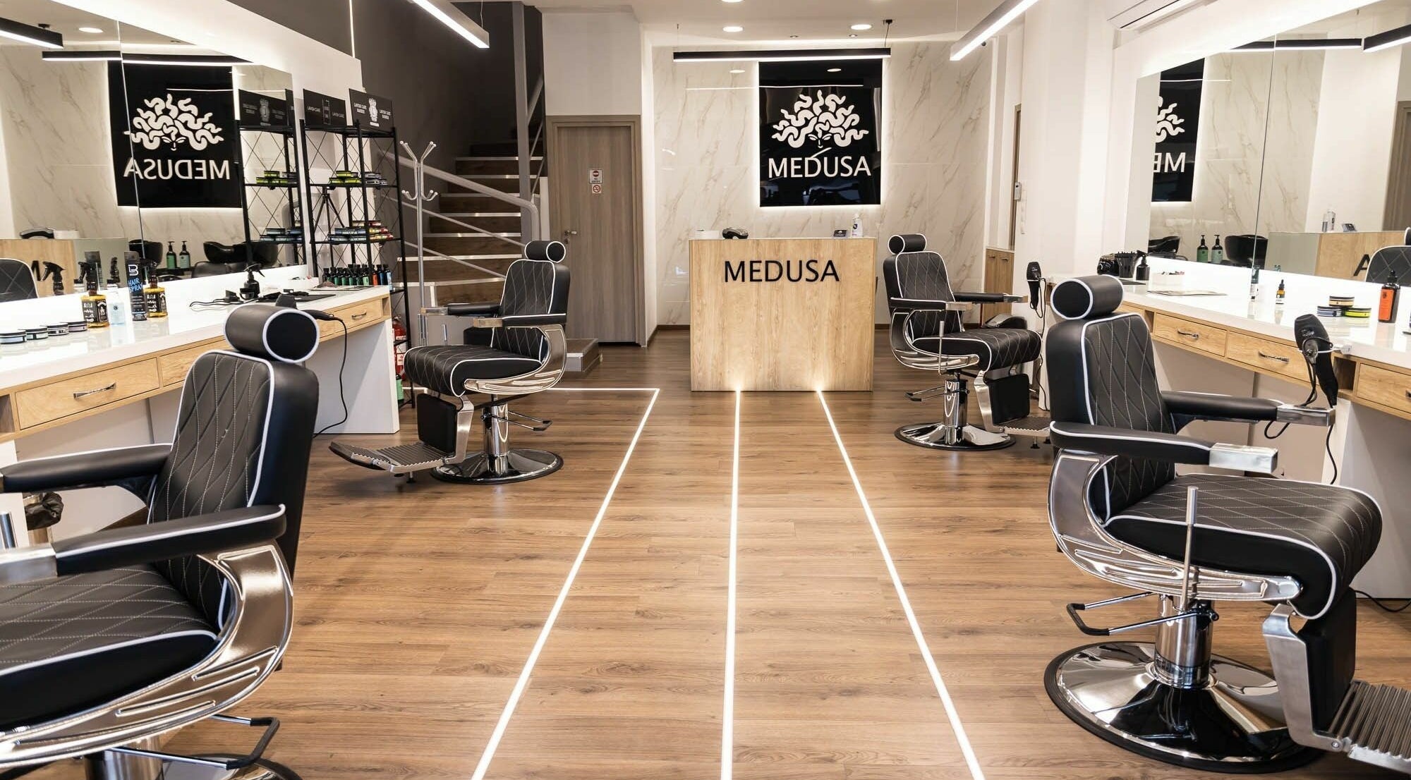 Εσωτερικό του κομμωτηρίου Medusa Barber στη Θεσσαλονίκη, GR με κομψές καρέκλες και καθρέφτες.