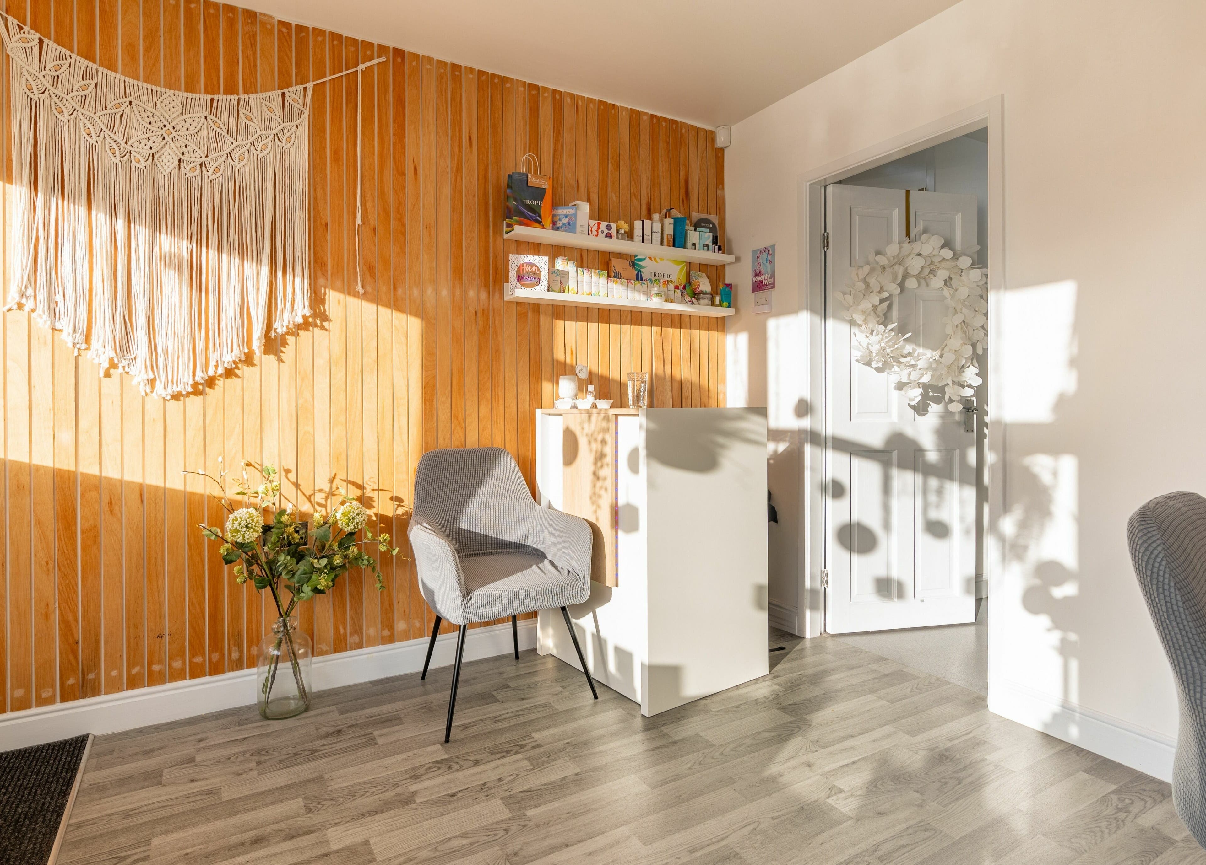 Radiate Health and Beauty in Stockport, England. A calming space with a chair, wooden wall, and soft lighting.