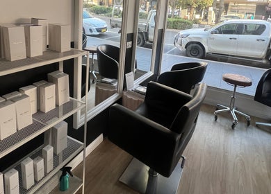 Modern salon interior at Hair Artistry Studio, Camden, New South Wales, AU with sleek chairs and product shelves.