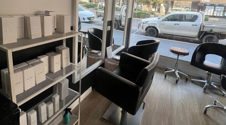 Modern salon interior at Hair Artistry Studio, Camden, New South Wales, AU with sleek chairs and product shelves.