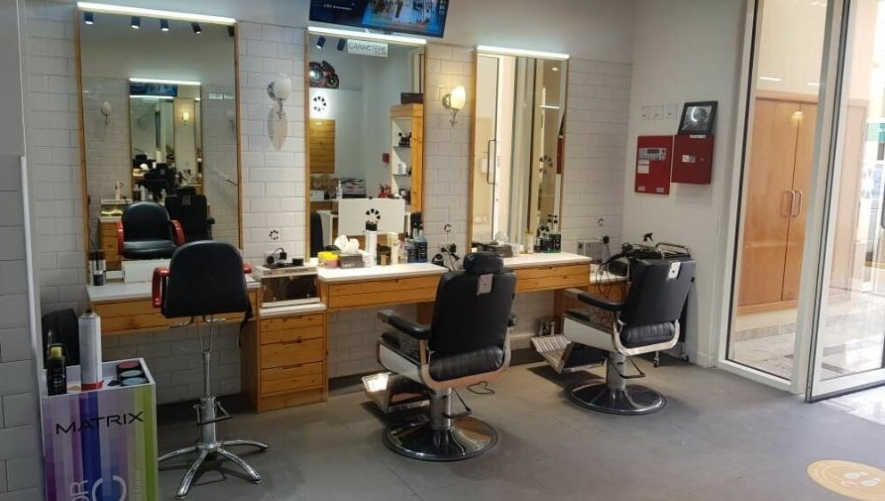 Interior of Caractere Remraam Gents barbershop in Dubai, AE, featuring stylish chairs and mirrors.