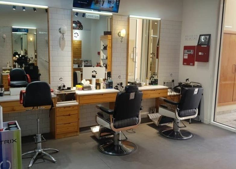 Interior of Caractere Remraam Gents barbershop in Dubai, AE, featuring stylish chairs and mirrors.