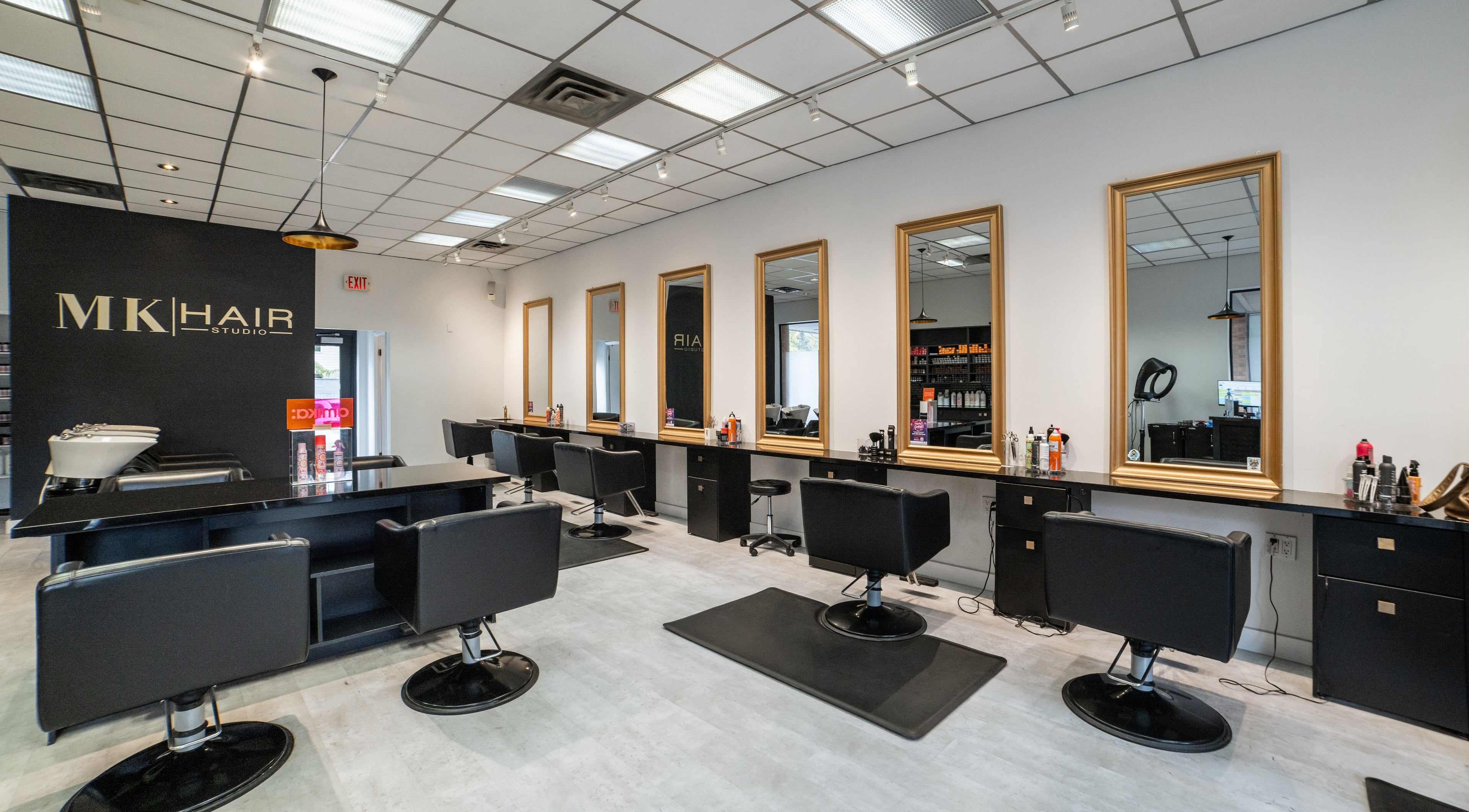 Modern interior of Mk Hair Studio in Mississauga, Ontario, CA with stylish black chairs and mirrors.