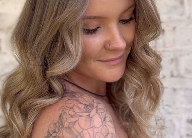 Close-up of a woman with wavy hair and floral tattoo at Cai The Stylist, Benoni, Gauteng, ZA.