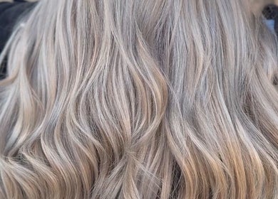 Luxurious silver-blonde waves styled at Cai The Stylist, Benoni, Gauteng, ZA, showcasing expert color blending.