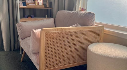Cozy lounge area at Enhanced Beauty, Westport, West Coast, NZ with plush seating by a sunlit window.