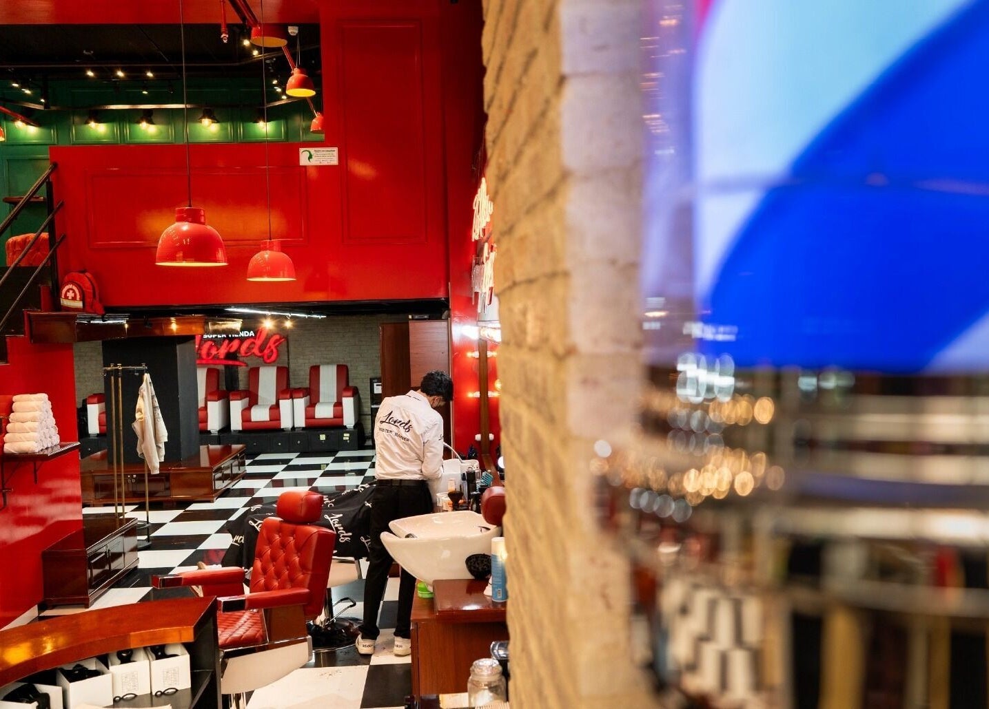 Interior moderno de Barberia Lords ®️ C.C. Hayuelos en Bogotá, Bogotá, CO con sillas rojas y decoración sofisticada.